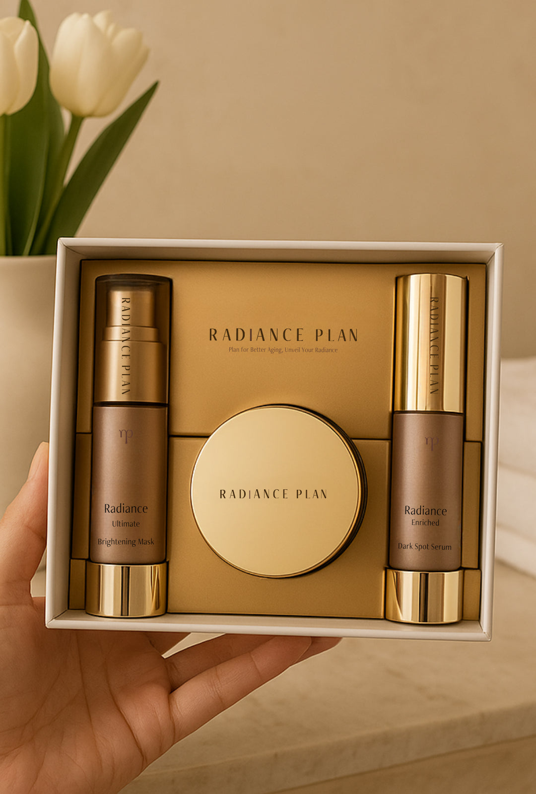 Three gold and beige skincare product bottles on a matching background.